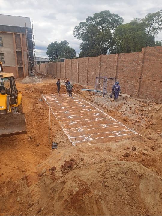 Marked-out excavation area with a backhoe loader and workers on a construction site