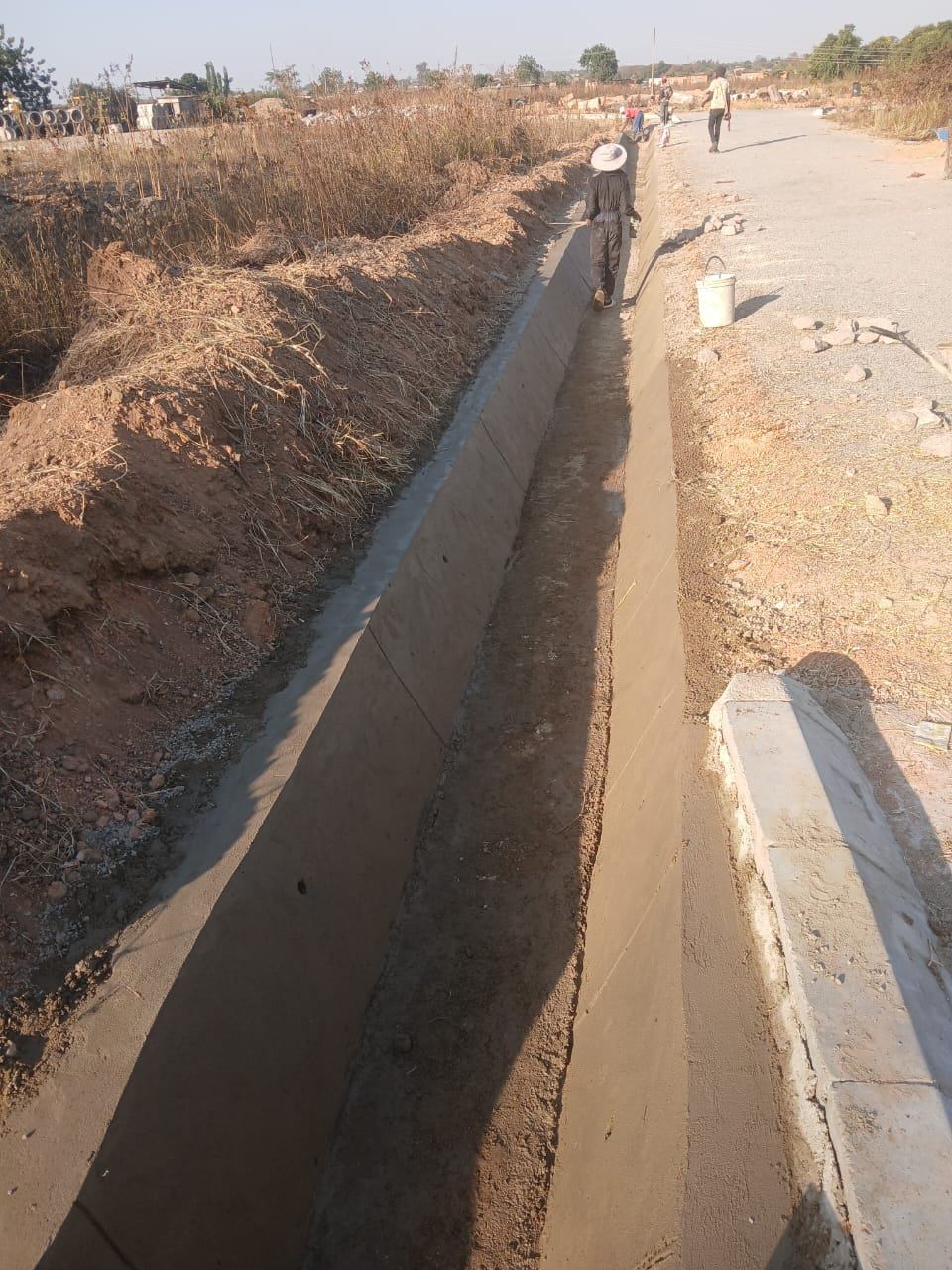 Concrete-lined stormwater channel running beside a gravel road in Graylands