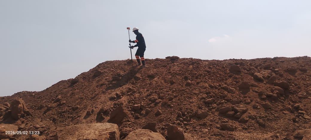 Surveyor holding a GNSS pole on top of a large stockpile during a volumetric survey
